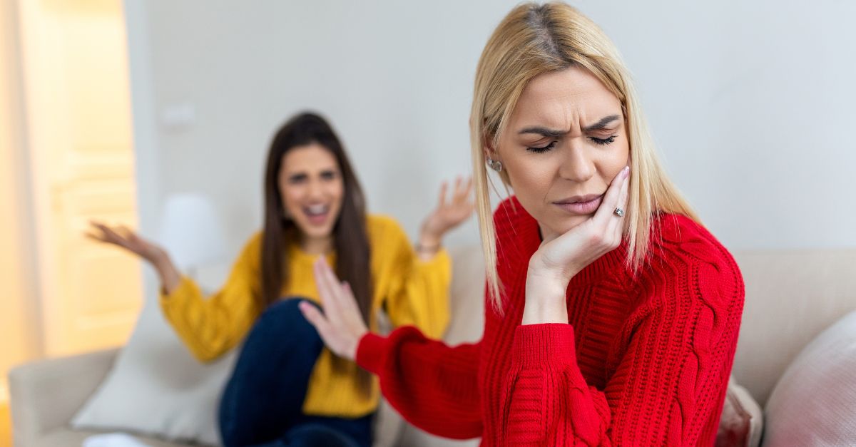 Two female friends sitting on sofa and arguing with each other. Frie