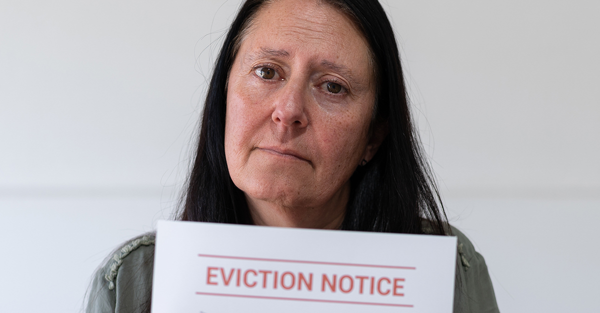 Sad woman looking at the camera and holding an eviction notice. Concept of not paying rent.