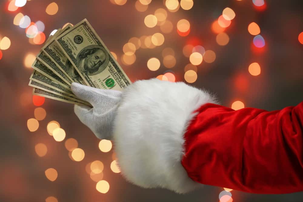 Santa,Claus,Holding,Money,Against,Defocused,Lights