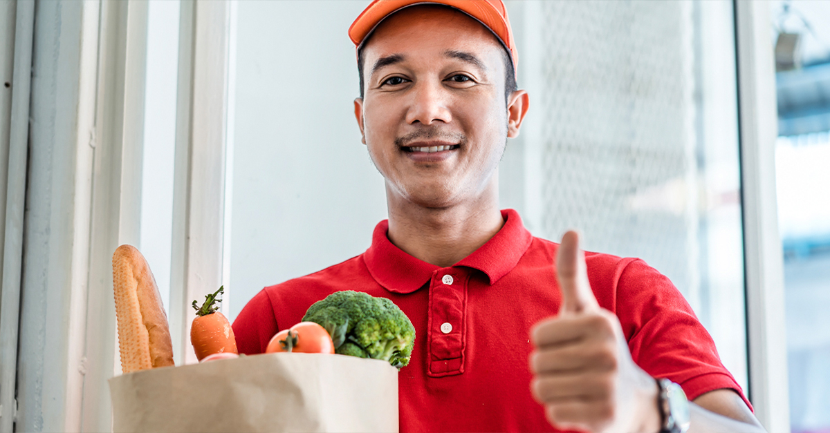 Delivery man giving a thumbs up, delivering groceries.