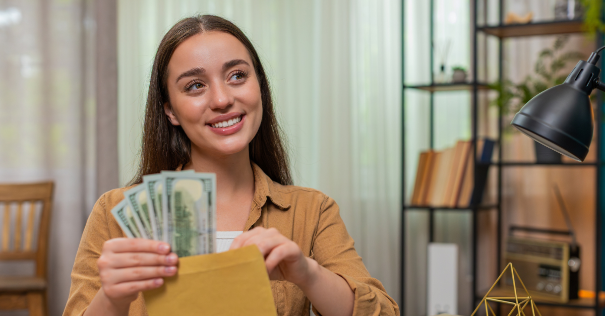 Young woman at home table counts dollars income cash