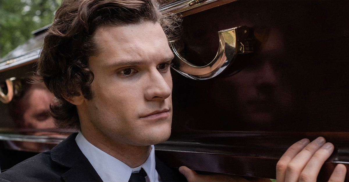 A solemn moment as a man carries a coffin during an outdoor funeral procession.