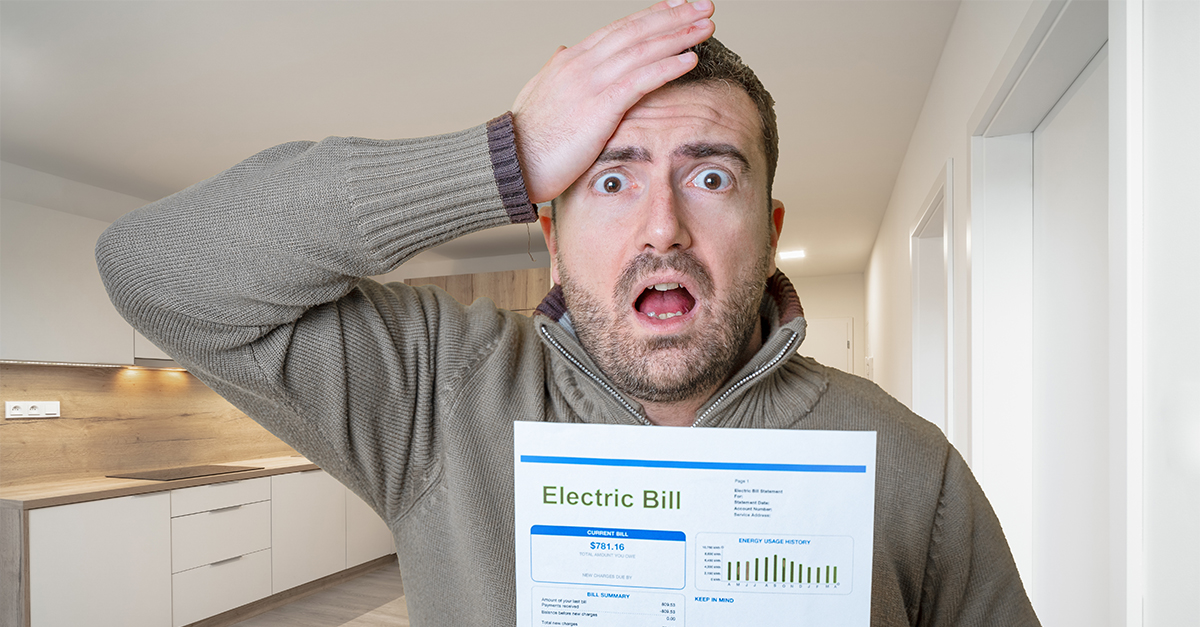 Shocked man reading some bills energy expenses isolated on yellow background