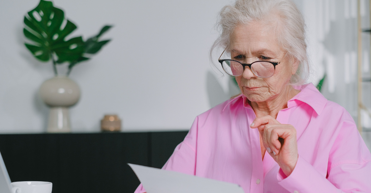 an-elderly-woman-in-pink-long-sleeves-looking-at-documents-while-sitting