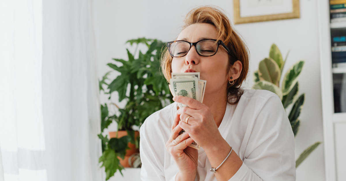 /woman-in-white-long-sleeve-shirt-kissing-banknotes