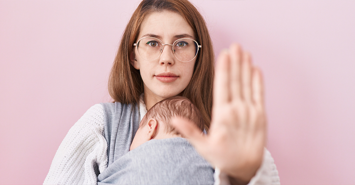 Young caucasian woman holding and carrying baby on a sling