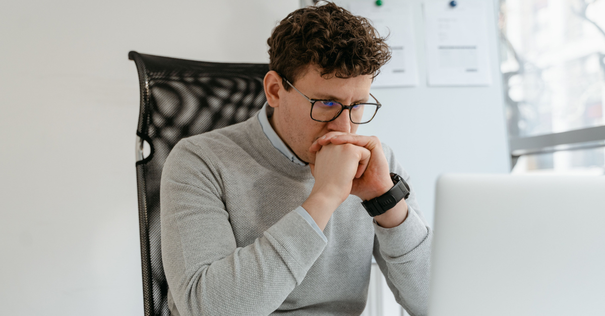 a-man-in-gray-sweater-staring-at-his-laptop